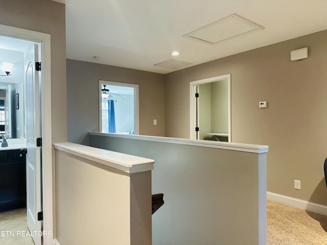 corridor with attic access, baseboards, light carpet, and an upstairs landing