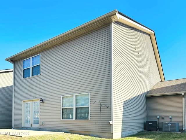 rear view of property featuring a yard and central air condition unit