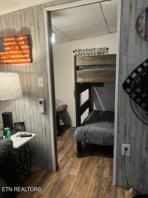 bedroom with dark hardwood / wood-style flooring and wood walls