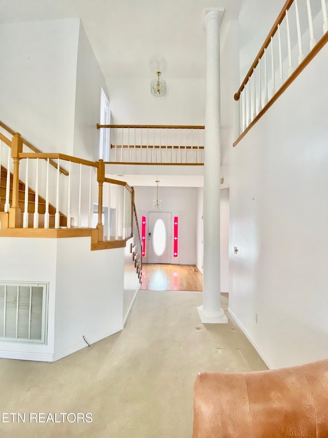 carpeted foyer with decorative columns and a high ceiling