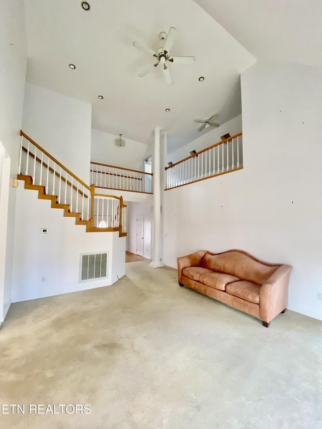 unfurnished living room with carpet, ceiling fan, and a high ceiling