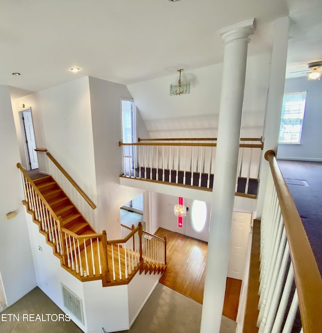 stairs featuring ceiling fan, wood-type flooring, and ornate columns