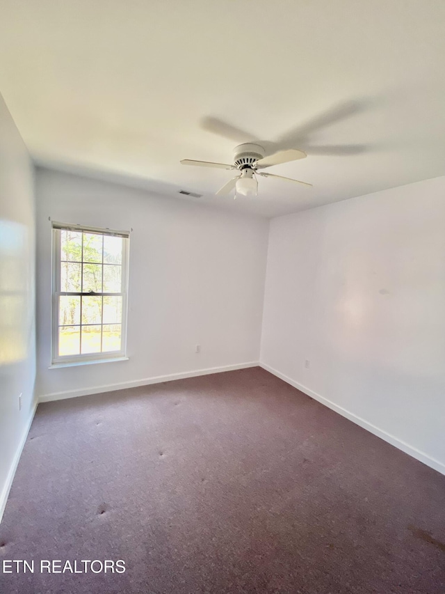 unfurnished room featuring ceiling fan and dark carpet