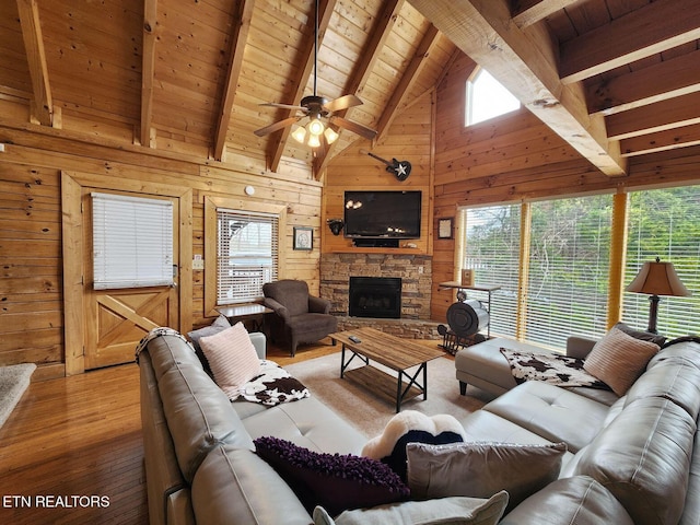 living room with a fireplace, a wealth of natural light, wooden walls, and beamed ceiling