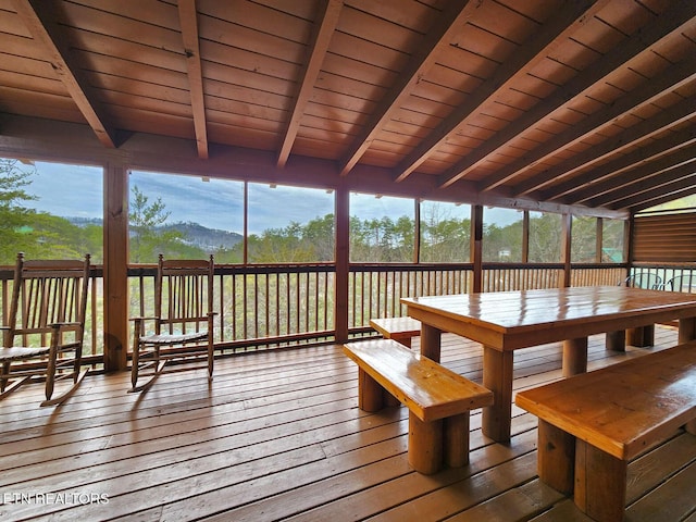 unfurnished sunroom with lofted ceiling with beams and a mountain view