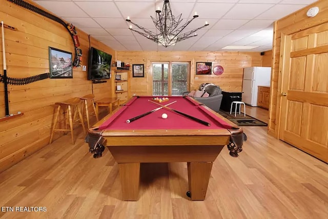 game room with light hardwood / wood-style flooring, wooden walls, and a paneled ceiling