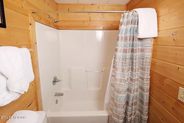 bathroom featuring toilet, shower / bath combination with curtain, and wood walls