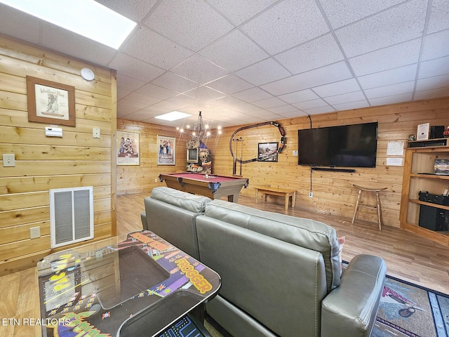 living room featuring pool table, wood-type flooring, a drop ceiling, and wood walls