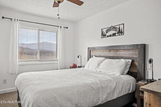 bedroom with ceiling fan, carpet floors, and a textured ceiling