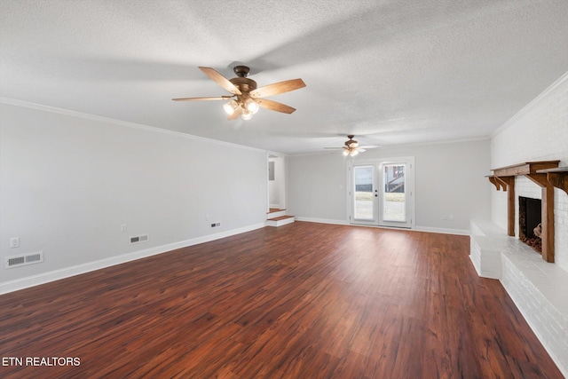 unfurnished living room featuring ornamental molding, a brick fireplace, dark hardwood / wood-style floors, and a textured ceiling