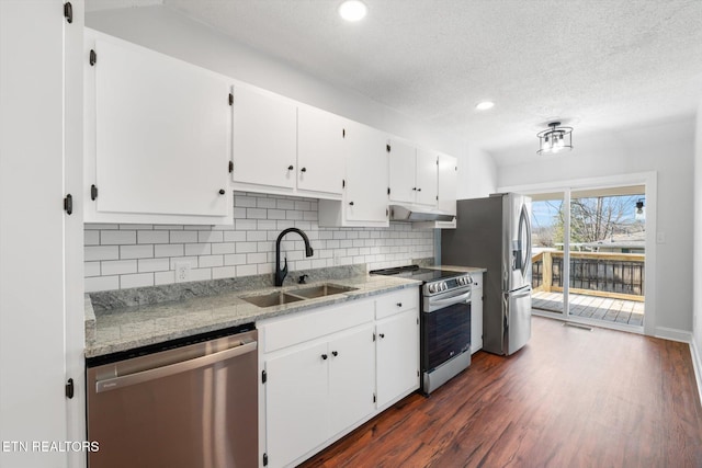 kitchen featuring stainless steel appliances, white cabinetry, sink, and light stone counters