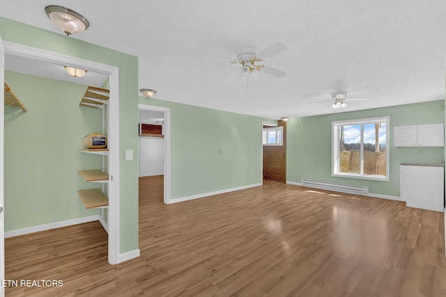 unfurnished living room with hardwood / wood-style flooring, ceiling fan, a textured ceiling, and baseboard heating