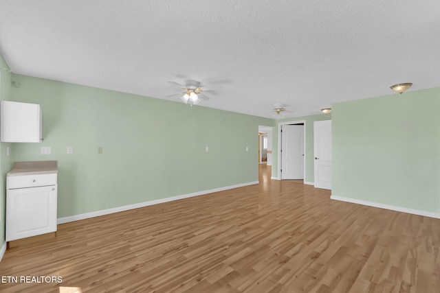 unfurnished living room featuring ceiling fan, light hardwood / wood-style floors, and a textured ceiling