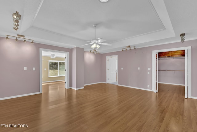 unfurnished room featuring hardwood / wood-style floors, a tray ceiling, rail lighting, and ceiling fan