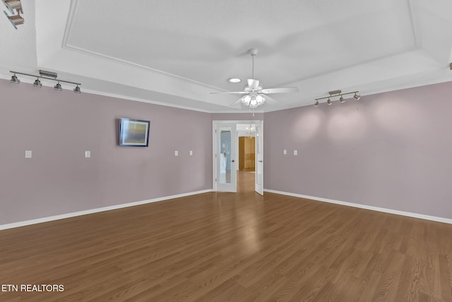 empty room with hardwood / wood-style floors, ceiling fan, and a tray ceiling