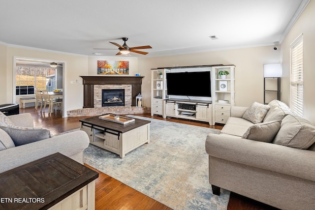 living room featuring hardwood / wood-style floors, a fireplace, ornamental molding, and ceiling fan