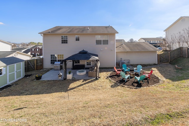 rear view of house with a patio area, a gazebo, a lawn, a storage unit, and a fire pit