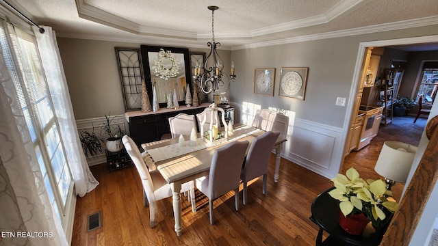 dining room with dark hardwood / wood-style flooring, a notable chandelier, ornamental molding, and a textured ceiling