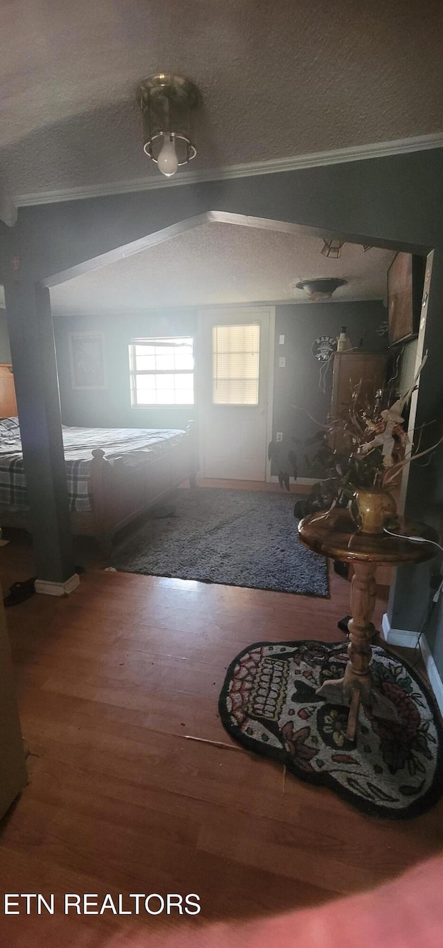 entryway featuring hardwood / wood-style flooring, ornamental molding, and a textured ceiling