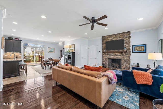 living room featuring dark hardwood / wood-style flooring, crown molding, a fireplace, and ceiling fan