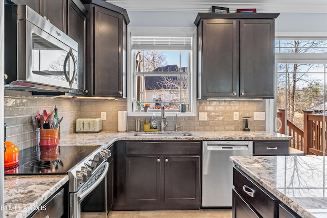 kitchen with sink, dark brown cabinets, ornamental molding, appliances with stainless steel finishes, and light stone countertops