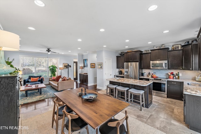 dining space with sink, crown molding, and ceiling fan