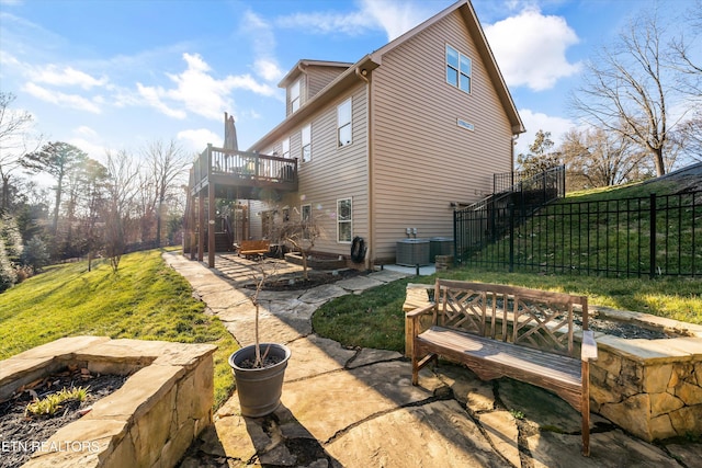 exterior space with cooling unit, a wooden deck, a patio area, and a lawn