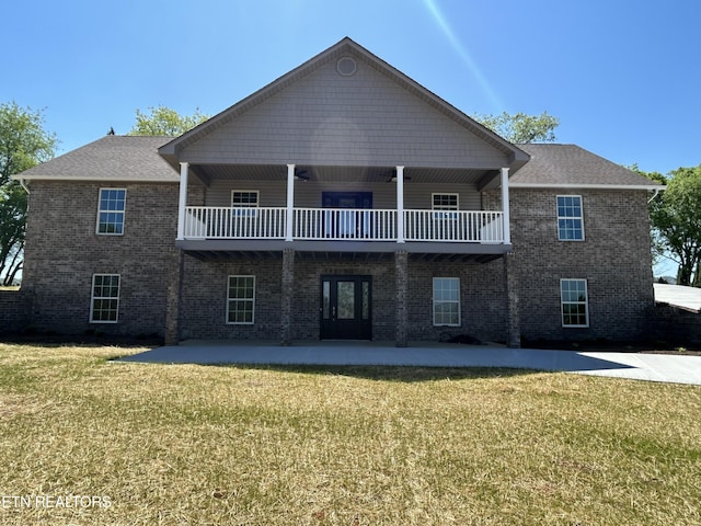 back of house featuring a yard, brick siding, and a balcony