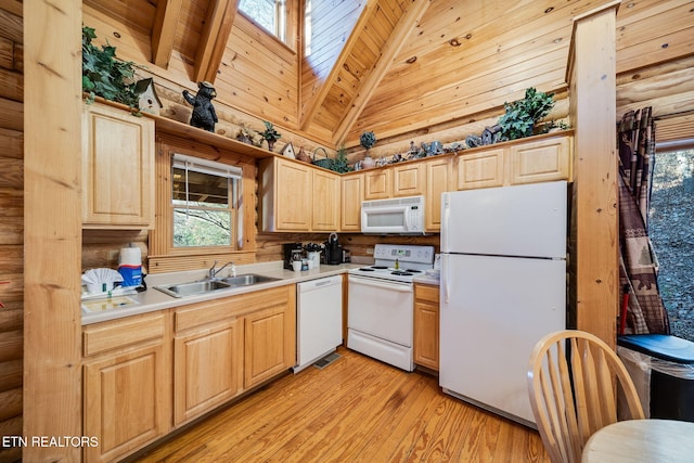 kitchen featuring white appliances, sink, light wood-type flooring, vaulted ceiling with skylight, and light brown cabinetry