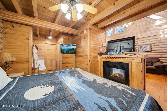 bedroom featuring hardwood / wood-style flooring, beamed ceiling, rustic walls, and wooden ceiling