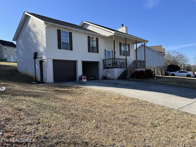 raised ranch featuring a garage, a porch, and a front lawn