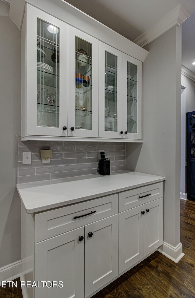 bar with backsplash, ornamental molding, dark hardwood / wood-style floors, and white cabinets