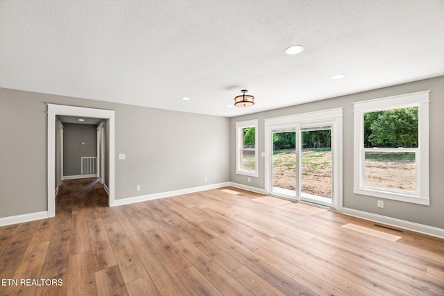 spare room featuring a textured ceiling and light hardwood / wood-style flooring