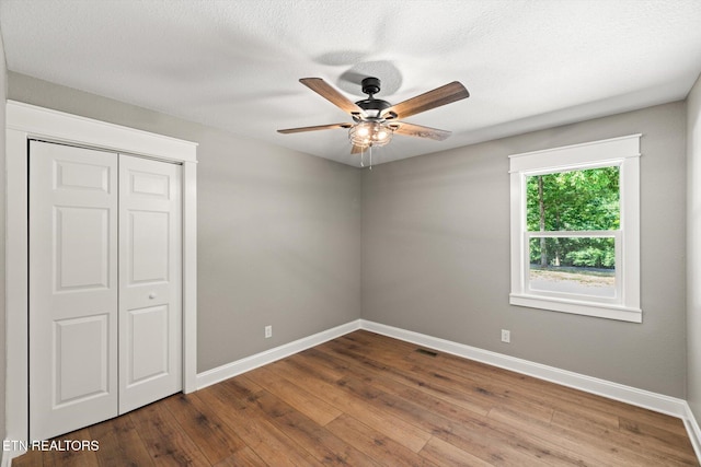 unfurnished bedroom featuring ceiling fan, hardwood / wood-style floors, a closet, and a textured ceiling