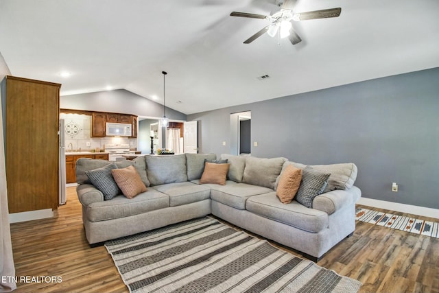 living room featuring ceiling fan, lofted ceiling, sink, and wood-type flooring