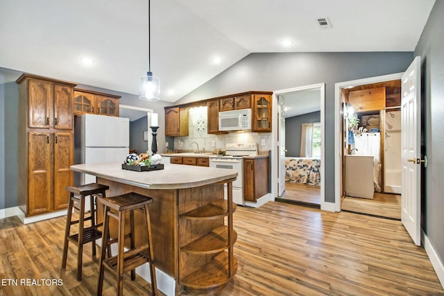 kitchen with white appliances, lofted ceiling, light hardwood / wood-style floors, and hanging light fixtures