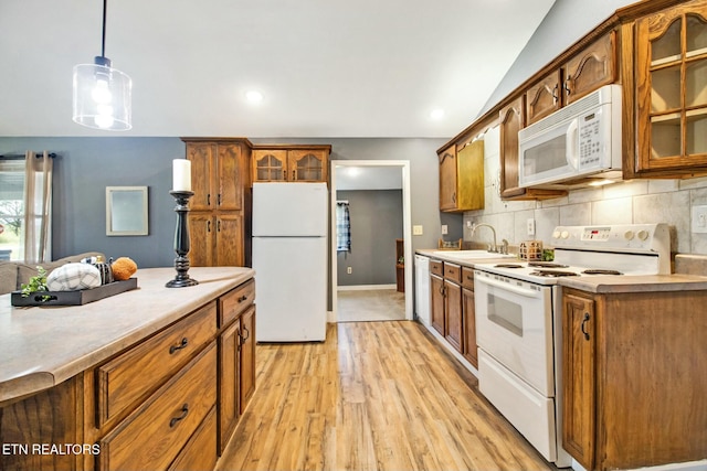 kitchen featuring sink, white appliances, light hardwood / wood-style flooring, hanging light fixtures, and tasteful backsplash