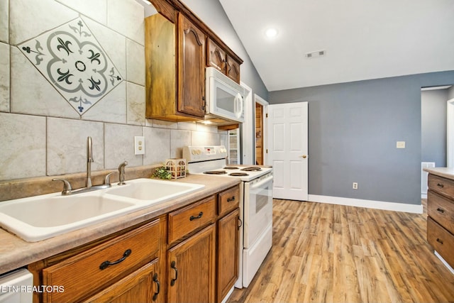 kitchen with sink, white appliances, light hardwood / wood-style flooring, backsplash, and vaulted ceiling