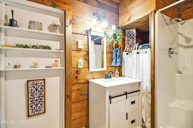 bathroom featuring walk in shower, vanity, and wood walls