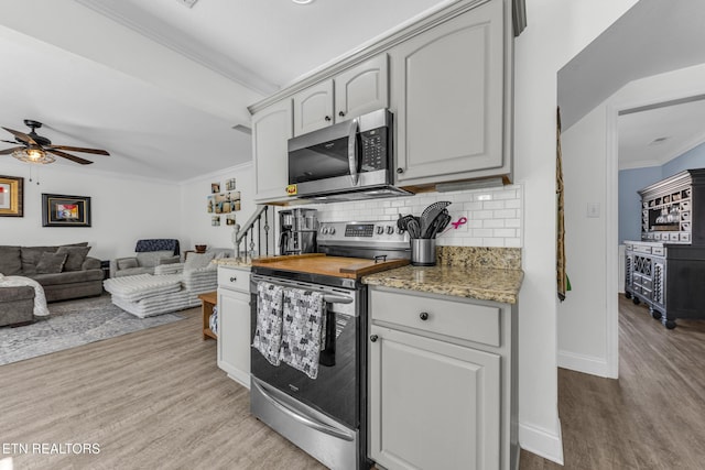 kitchen with crown molding, appliances with stainless steel finishes, light wood-type flooring, and backsplash