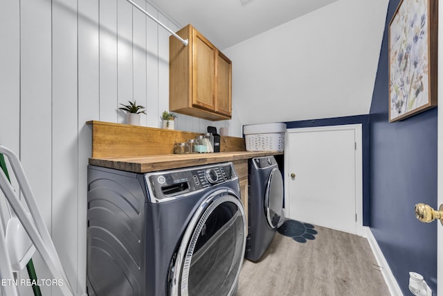 laundry area with cabinets, independent washer and dryer, and light hardwood / wood-style floors