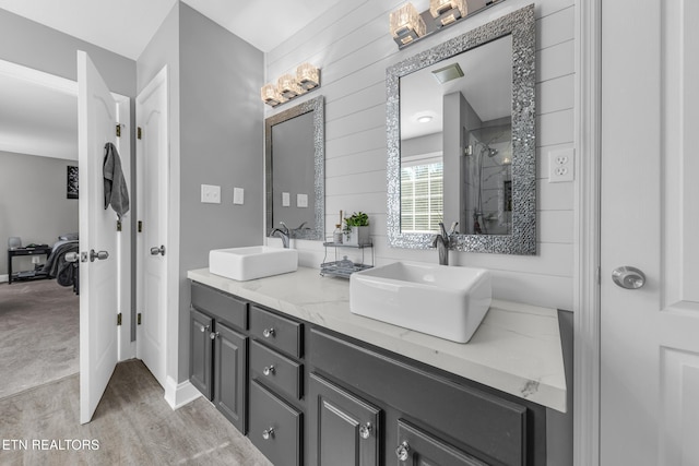 bathroom with hardwood / wood-style flooring, vanity, wooden walls, and a shower