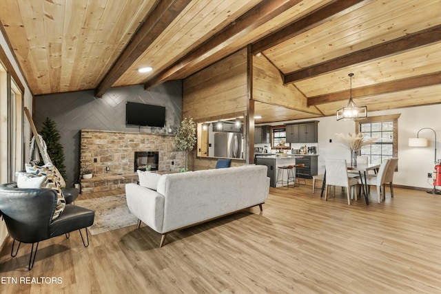 living room with a brick fireplace, vaulted ceiling with beams, wood ceiling, and light hardwood / wood-style floors