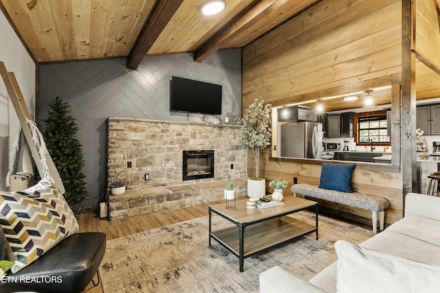 living room featuring a stone fireplace, wood ceiling, wooden walls, beam ceiling, and light hardwood / wood-style floors