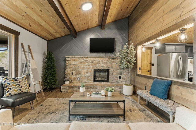 living room featuring beam ceiling, wood-type flooring, wooden ceiling, and a fireplace