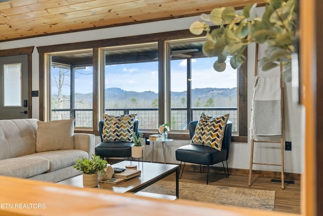 living room with wood-type flooring, a mountain view, and wood ceiling