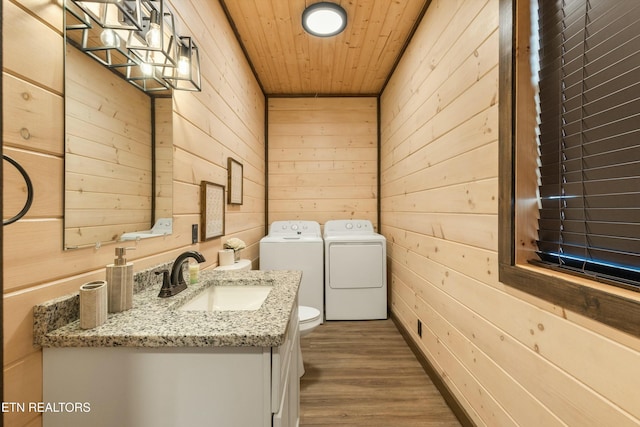 laundry area featuring sink, wooden ceiling, wooden walls, hardwood / wood-style floors, and washing machine and dryer