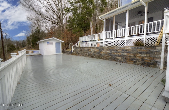 wooden terrace featuring ceiling fan, a storage shed, and a sunroom