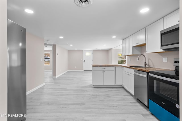 kitchen featuring sink, stainless steel appliances, white cabinets, and light wood-type flooring