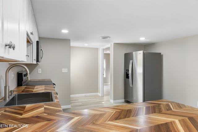 kitchen with white cabinetry, appliances with stainless steel finishes, sink, and light parquet floors